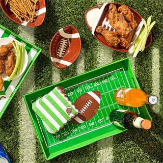 Football-themed snack platter with wings, fries, and a bottle of beer on a grass-like surface.