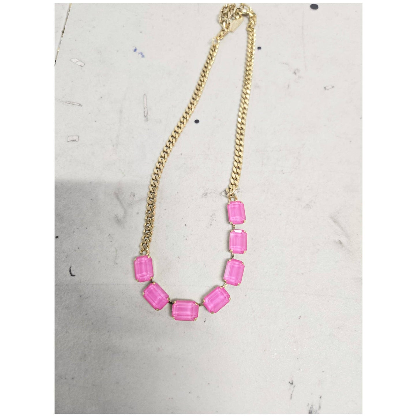 Necklace with pink beads on a gold chain against a light gray background
