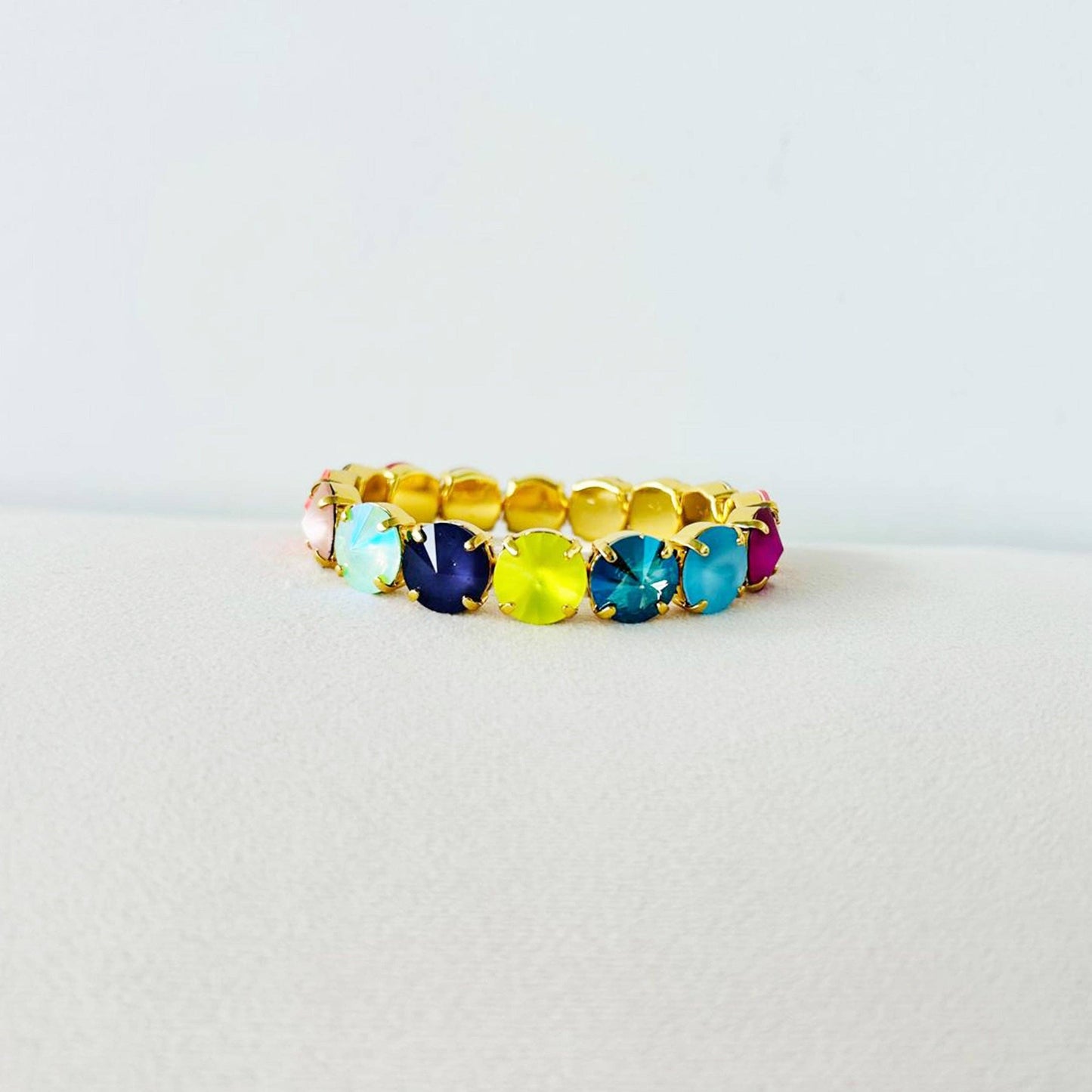 Gold ring with multicolored gemstones on a light gray background