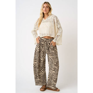 Woman wearing a white lace top and zebra print pants on a white background