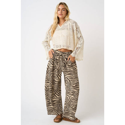 Woman wearing a white lace top and zebra print pants on a white background
