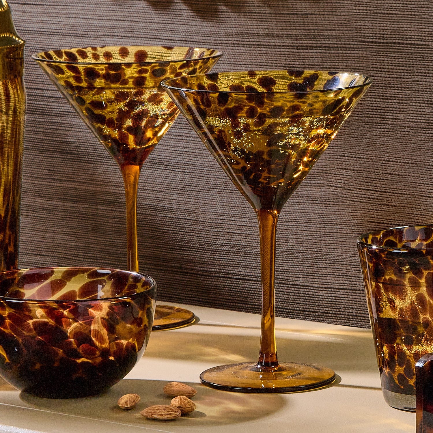 Leopard print glassware including martini glasses and a bowl on a textured surface. Tortoise shell martini glasses