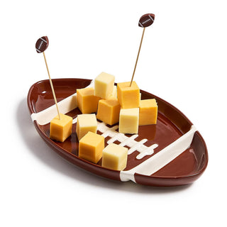 Football-shaped platter with cheese cubes and toothpicks on a white background