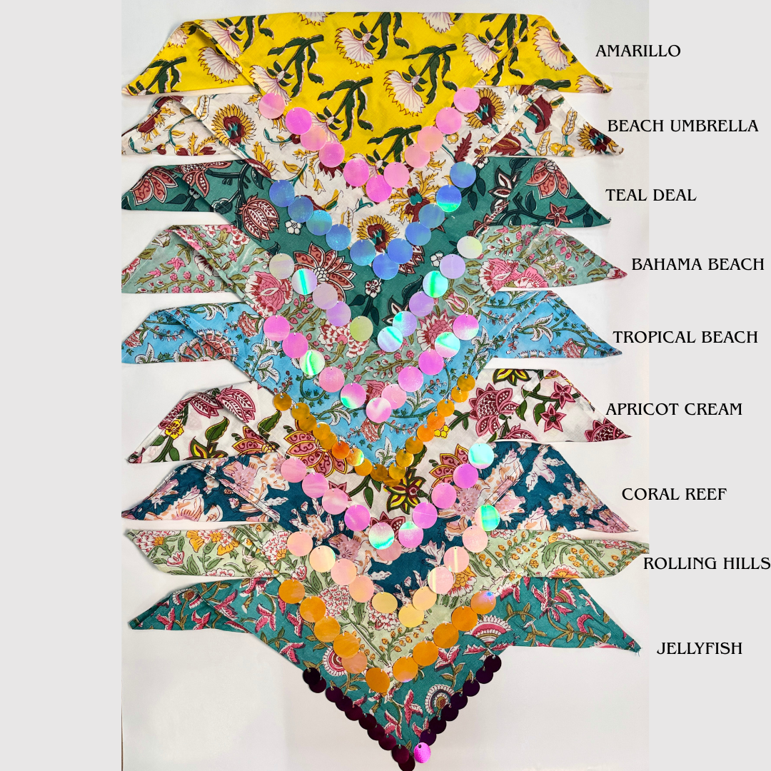 A vertical stack of eight different printed fabric necklaces or collar-style accessories, each decorated with rows of iridescent round sequins. Each piece is labeled with a name like Amarillo, Beach Umbrella, Teal Deal, Bahama Beach, Tropical Beach, Apricot Cream, Coral Reef, Rolling Hills, and Jellyfish on a plain white background.