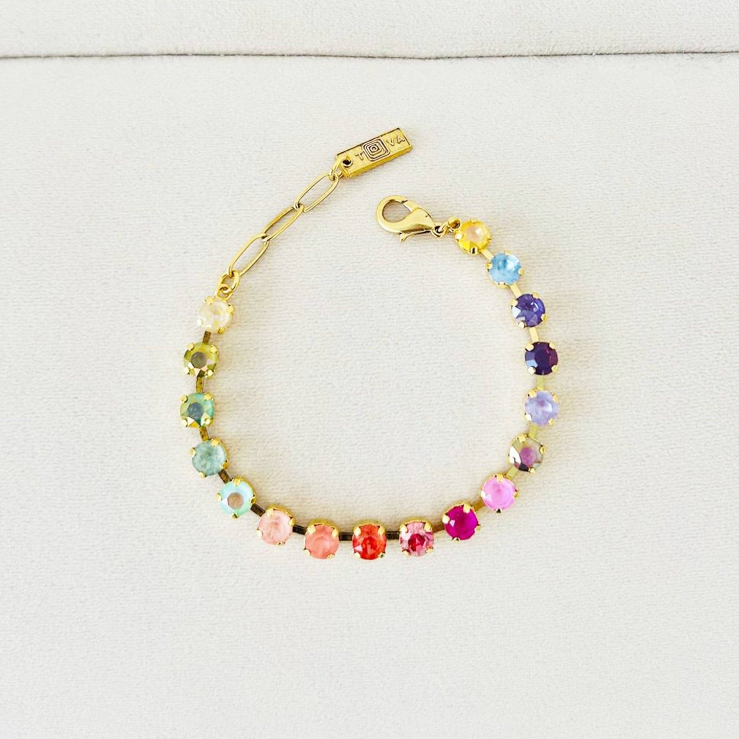 Multicolored beaded bracelet with gold clasp on a light gray background
