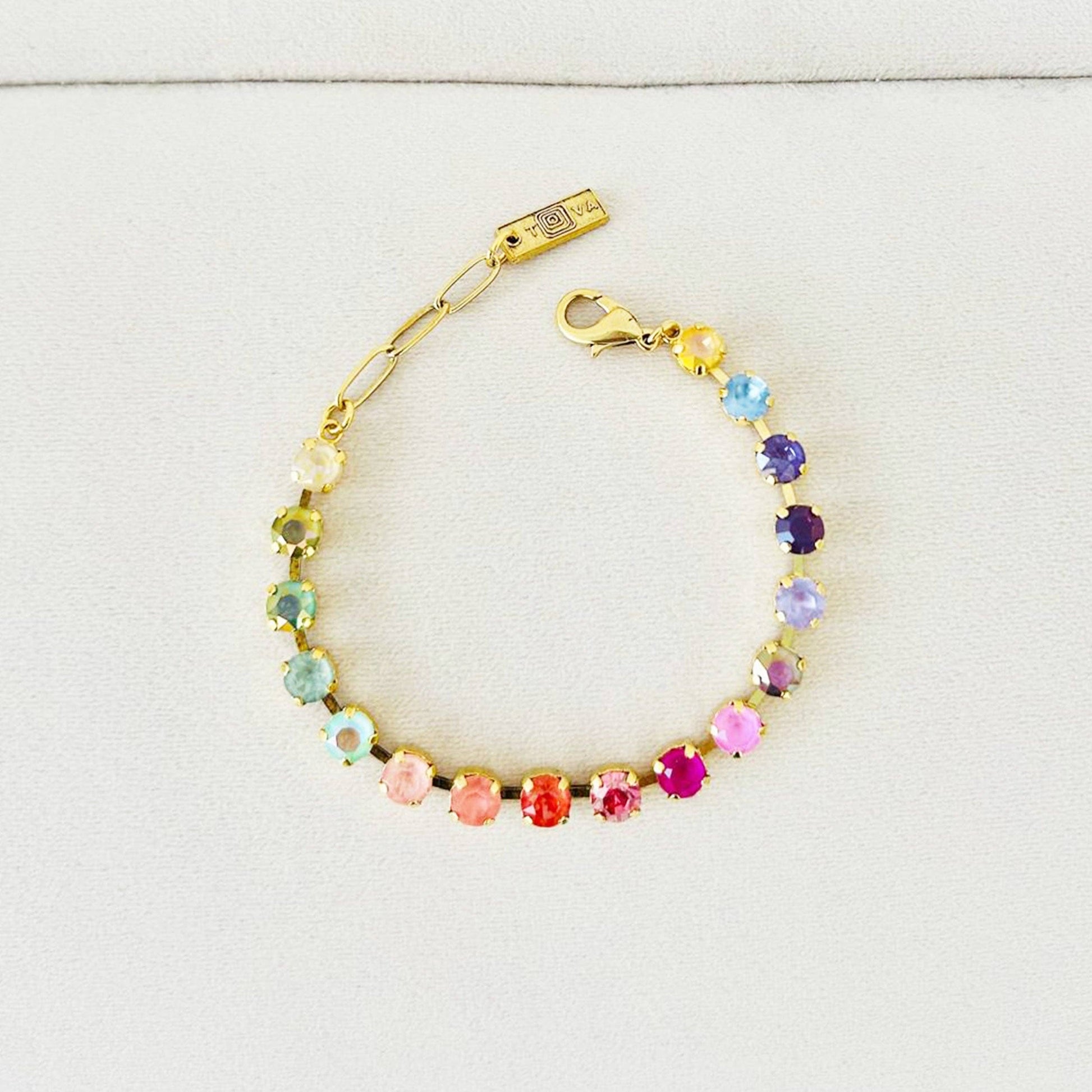 Multicolored beaded bracelet with gold clasp on a light gray background