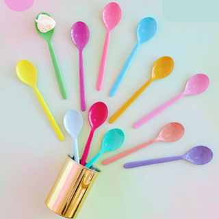 A collection of multicolor serving spoons arranged in a circular pattern on a pastel background.