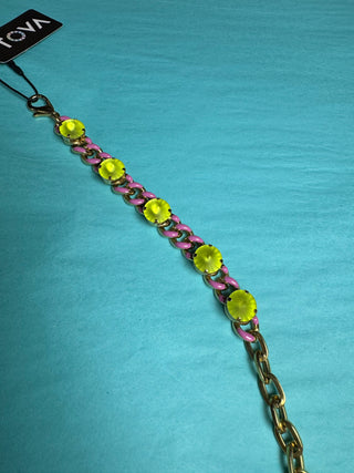 A gold-tone chain bracelet with alternating pink and lime green links, featuring large round lime green stones, shown on a textured turquoise background with a black Vova brand tag.