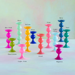 Colorful Glitterville glass candle holders with labeled colors on a gradient background