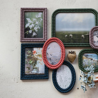Collection of decorative picture frames with various photos on a textured wall.