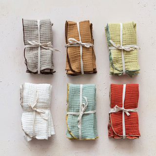 Set of six folded fabric swaddles in various colors on a light background