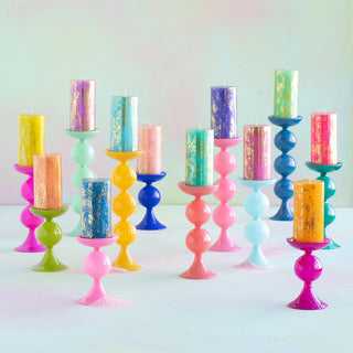 Colorful Glitterville glass pillar candle holders with candles on a light background