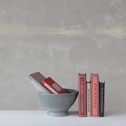 Gray bowl with books inside and a stack of books on a gray surface