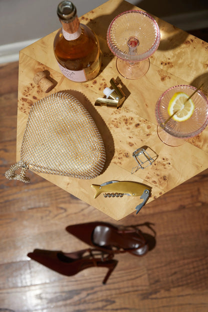 Bottle of wine, glasses with lemon slices, and a mesh bag on a wooden surface.