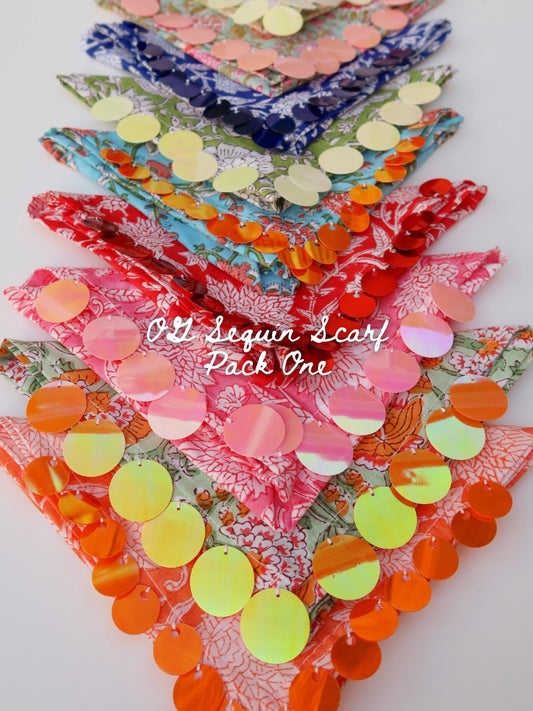 A collection of triangular scarf banners decorated with colorful sequins, arranged diagonally on a white background. The scarves feature various floral and patterned fabrics in pink, red, blue, green, and orange, embellished with circular sequins in shades of orange, yellow, pink, and blue.