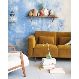 Living room with mustard yellow sofa, white chair, and decorative items against a blue wall.