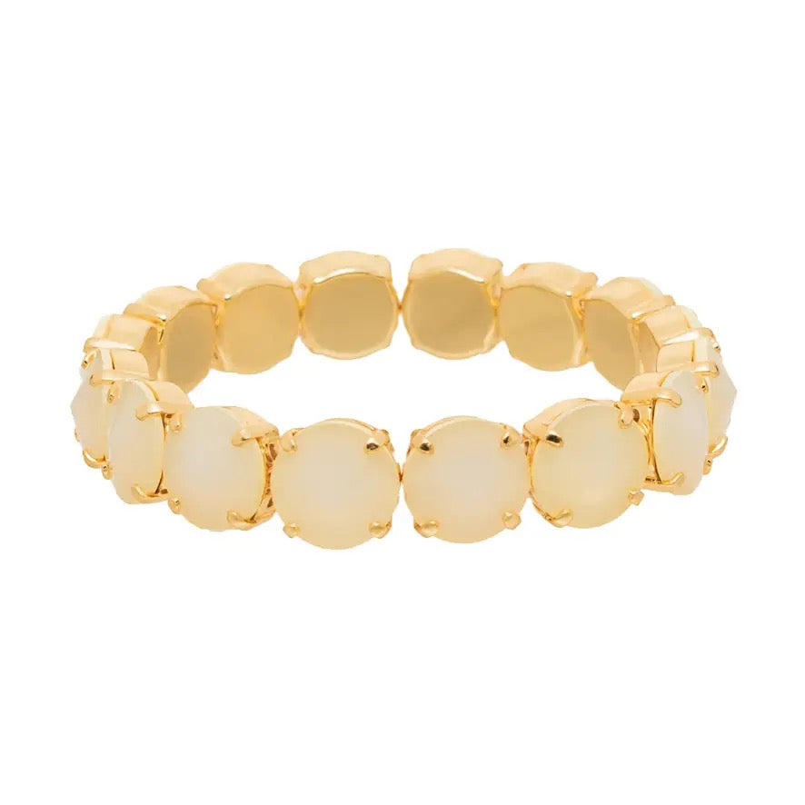 A gold-plated stretch bracelet featuring a row of round, faceted cream cabochon stones set in gold, shown against a plain white background.