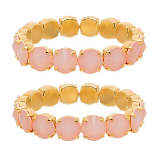 Two matching gold-plated stretch bracelets, each featuring a row of round, pale pink cabochon gemstones in prong settings, shown against a plain white background.