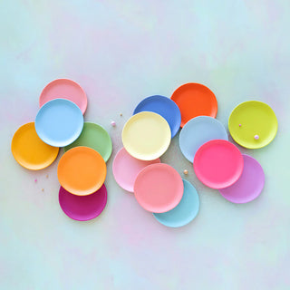 A collection of colorful, round melamine plates in various cool and warm tones, arranged in an ombre effect.