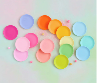 A collection of colorful, round melamine dessert plates arranged in a rainbow pattern.