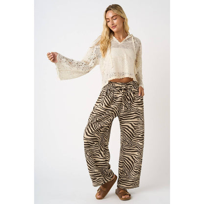 Woman wearing a white lace top and zebra print pants on a white background