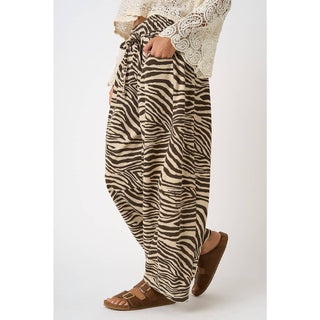 Zebra print pants worn with a white lace top on a plain background