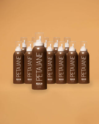 Multiple bottles of Peta Jane hair product arranged in a pyramid formation on an orange background.