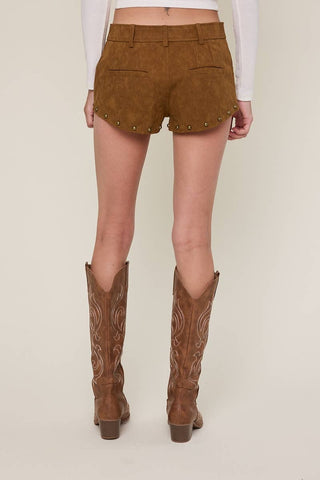 Person wearing brown suede shorts and boots on a plain background