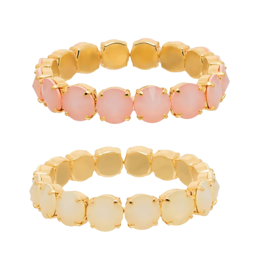 Two gold-plated beaded stretch bracelets shown on a plain white background. The top bracelet features round, dusty pink beads, while the bottom bracelet features round, milky white beads.